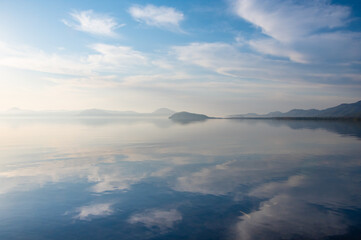 Fototapeta na wymiar 白い雲の浮かぶ青空を水面に反射する湖。日本の北海道の屈斜路湖。