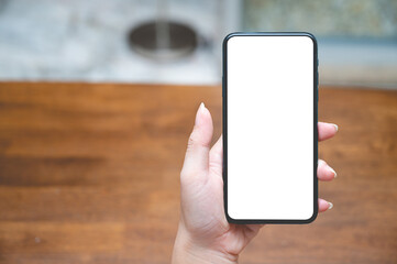 Close up women using a smartphone with an empty white screen at the wooden interior cafe.