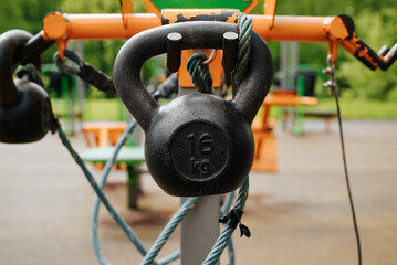 Outdoor sports ground with set of weights for weightlifting training in park, outdoors. Selective focus on 16 kg iron gym kettlebells.