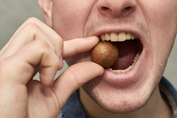 a man tries to crack a macadamia nut with his teeth