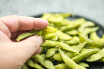 Green edamame with fingers picking up