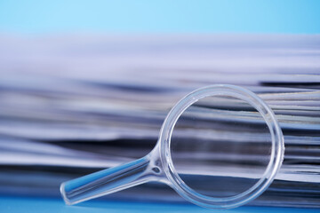 selective focus magnifying glass leans against a thick stack of documents.