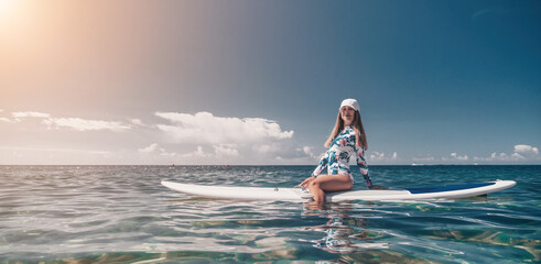 Healthy happy fit woman in bikini relaxing on a sup surfboard, floating on the clear turquoise sea...
