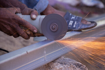 a worker is cutting mild steel with a machine, minimalist home industrial installation