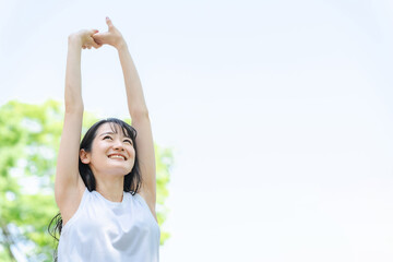 新緑の中でストレッチする女性（脱毛・ダイエット）
