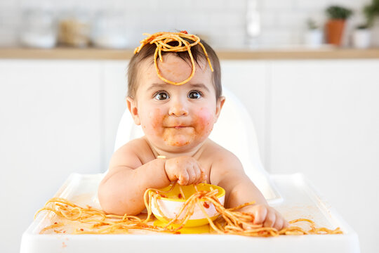 Cute baby eating spaghetti making funny face