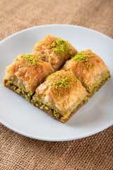 Pistachio baklava on a white plate.A plate baklava on fabric background