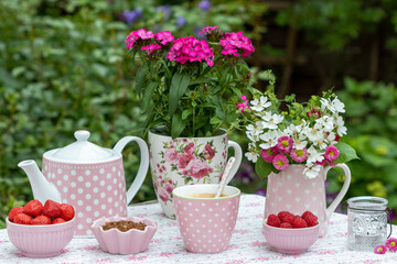 Tischdekoration mit Kaffeetasse, frischen Beeren und Blumen im Garten