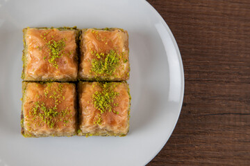 Pistachio baklava in a white plate on wooden background