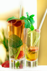 selective focus. cold summer drink with ice in a glass with a straw. Strawberry mojito cocktail in a glass with fresh mint, fresh strawberries and lime. detox refreshing drink on a light background. 