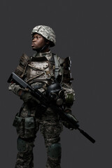 Portrait of african military man dressed in modern camouflage uniform holding rifle.
