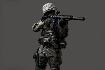 Portrait of brave army man dressed in modern camouflage uniform aiming rifle.