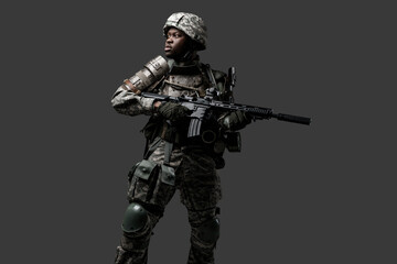 Photo of isolated on grey black soldier dressed in protective uniform posing with rifle.