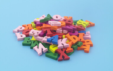 Heap of many colorful English letters on blue background.