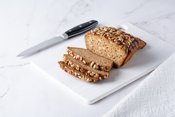 Sliced rye bread on a white table. Whole grain rye bread with seeds