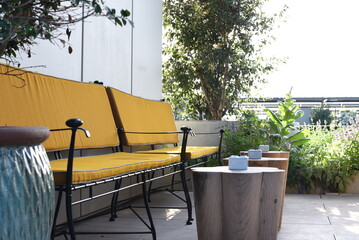 Beautiful terrace of the restaurant with ocher and blue shades of objects. Two yellow benches with...