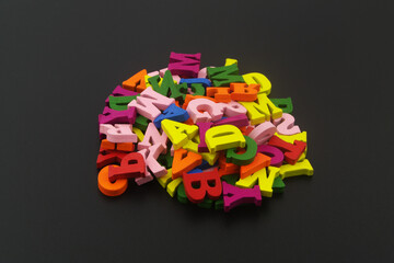 Heap of colorful letters on black background. Education concept.