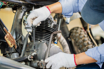Obraz premium Man repairing motorcycle in repair shop, Mechanic fixing motorbike in workshop garage, Repairing and maintenance concepts