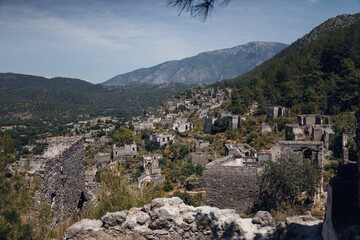 Ancient Greek abandoned city of Kayakoy in Fethiye, Turkey.  A city on a mountain. Destroyed, empty houses. Top view, drone shot. View of the abandoned city and the mountains behind in the background