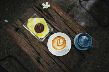 Latte coffee with chocolate cookie and drinking water on wooden table. 