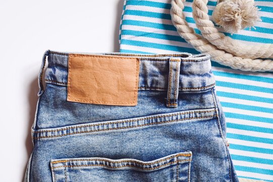 Stylish fashionable youth summer clothes image. Light blue jeans and cotton striped beach bag. Summer travel clothing close-up photo