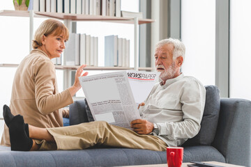Portrait of senior couple in living room, Elderly woman and a man reading a newspaper on cozy sofa at home, Family concepts