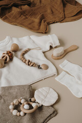 Aesthetic Scandinavian newborn baby clothes, care accessories, toys on neutral pastel beige colour background. Trendy elegant luxury infant set