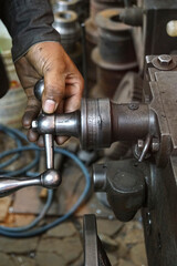 Closeup of a hand crank with mechanics closely operating the machine, scale of old Lathe Machinery. Vintage Industrial Machinery in a old factory. Selective focus.