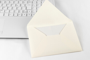 ノートパソコンのキーボードと手紙の封筒。メールのイメージ