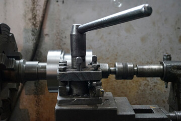 Closeup of a metal shaft parts cutting by old Lathe Machinery. lathe chuck and key 4-jaw screw chuck. Vintage Industrial Machinery in a old factory. Selective focus.