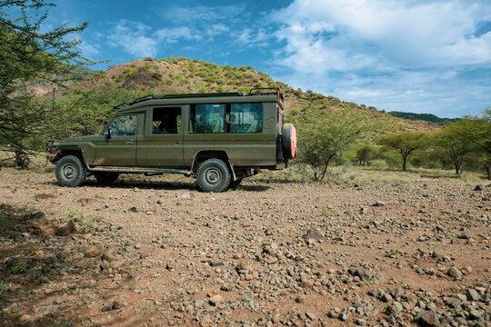 A toyota landcruiser in the wild against a mountain background at Shompole Hill, Kenya