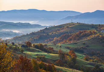 Fototapeta premium Foggy early morning autumn mountains scene. Peaceful picturesque traveling, seasonal, nature and countryside beauty concept scene. Carpathian Mountains, Ukraine.