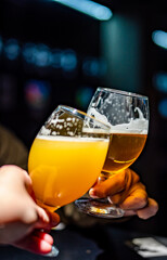 Two friends hands toasting with glasses of light beer at the pub or bar
