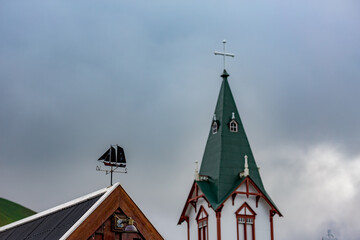 Tin boat showing the world directions. Blurred church tower in the background. Iceland in the summer. Photographic travel around the island.