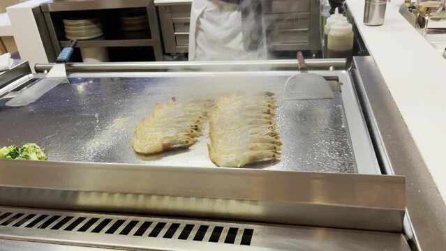 Zubereitung von frischen Garnelen, Meeresfr&uuml;chten auf einer hei&szlig;en Kochplatte.