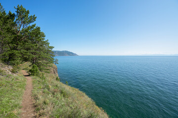 Fototapeta premium Lake Baikal coast, hill with forest, water bay. Summer travel, discovery of beauty of Earth. Siberia, Russia.