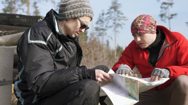 Team orienteering in the forest. Family travel with a map. Teamwork concept. Team of tourists in the forest park with a map. Tourists on a hike.