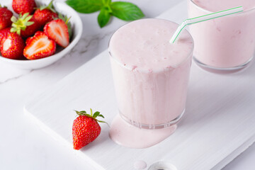 Yogurt , buttermilk or kefir with strawberry. Yogurt in glass on light background. Probiotic cold fermented dairy drink. Gut health, fermented products, healthy gut flora concept