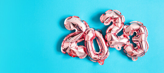 Foil pink balloons numbers 2023 on blue background. New year concept.