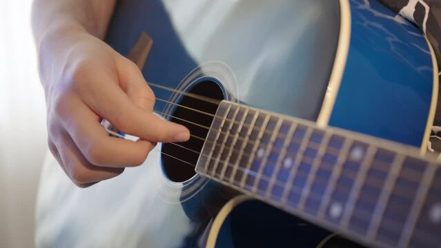 Close-up, male hands playing an acoustic six-string guitar. Musical instrument for recreation or hobby. Footage in real time. Guitar lessons at home