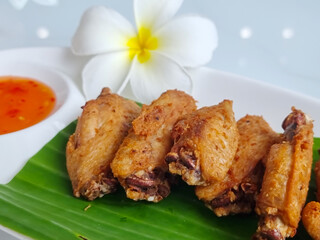 Fried chicken wings on a plate with rests and a cup of dipping sauce