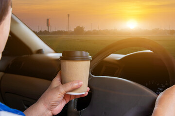 Asian woman drinking hot coffee takeaway cup inside a car and while driving the car in the morning during travel