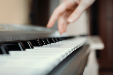 Fototapeta premium Synthesizer keys with selective focus and hand in the background, synth playing