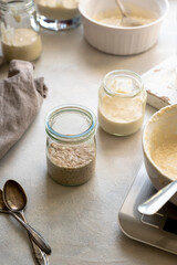 Sourdough starter in glass jars. Homemade breadmaking concept, busy lifestyle scene of baking at home. Sustainable living