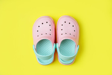 Pink kids clogs beach slippers on yellow background. Summer vacation concept. Fashion Sandals Beach...