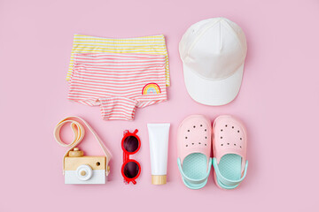 Swimsuit, sunglasses, beach slippers and sunscreen for children. Top view of beach accessories for kids.  Summer vacation concept.