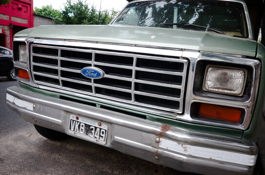 Buenos Aires, Argentina - January, 2020: Close-up of radiator grille, headlights, hood and chrome bumper with rust of old classic american 80s Ford F-100 pickup truck with argentinian license plate
