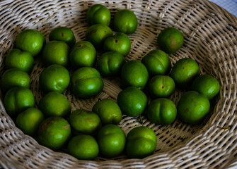 Green cherry plum in white straw plate