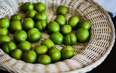 Green cherry plum in white straw plate