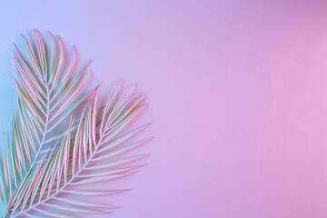 Fototapeta na wymiar Top view of tropical leaves in vibrant gradient holographic neon colors. Flat lay. Minimal surreal summer concept with copy space.